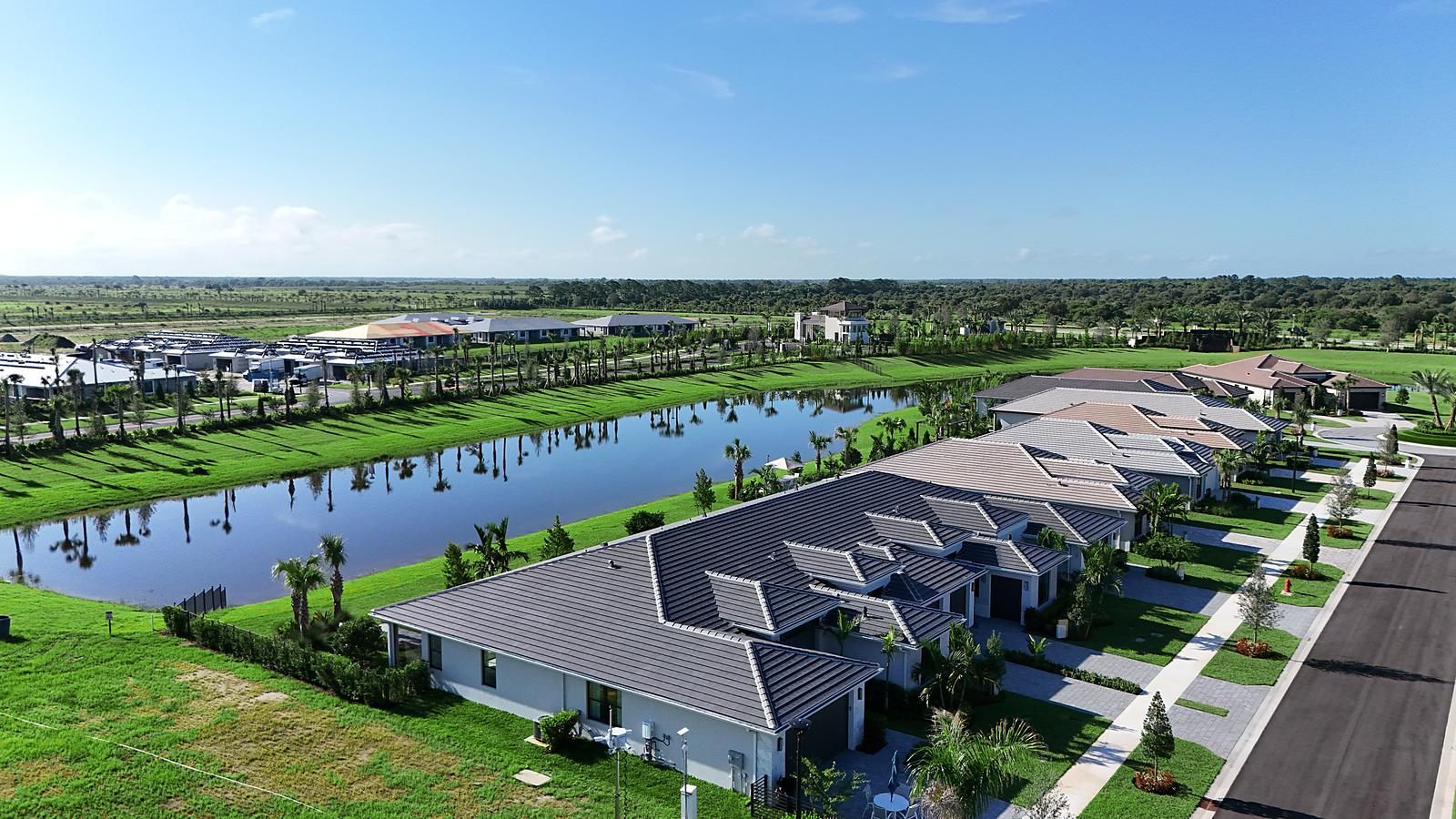 Finished homes with a palm-lined lake behind at Catalina Palms